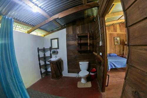 a bathroom with a toilet and a bed in a room at Oski Lodge, Rain Forest Rincón de la Vieja in Upala