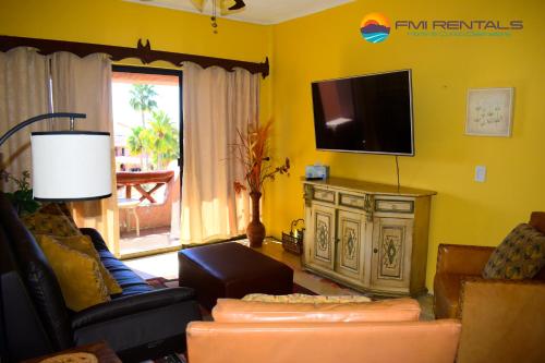 een woonkamer met een tv aan een gele muur bij Marina Pinacate B-319 in Puerto Peñasco