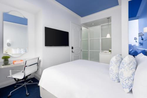 a bedroom with a bed and a desk and a television at NoMo SoHo in New York