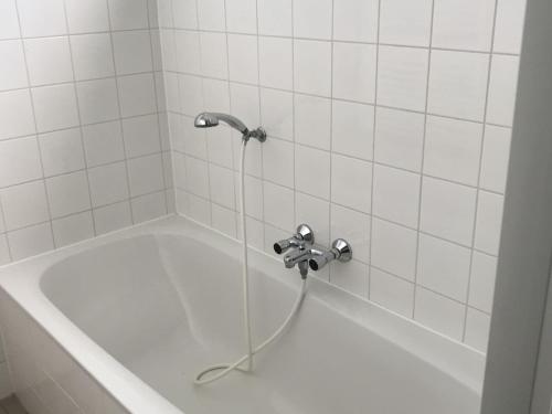 El baño incluye bañera con cabezal de ducha. en Comfy bungalow with a dishwasher, at the water en Medemblik