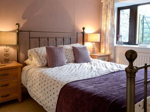 a bedroom with a bed with purple sheets and pillows at Hilltop Barn in Starbotton