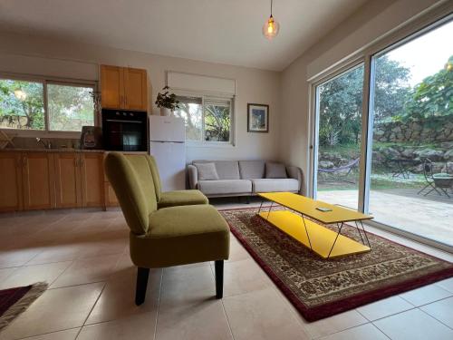 a living room with a yellow table and a chair at Alma BaHar - charming 2 bdrm house with garden עלמה בהר - דירת אירוח בלב גן פורח in Zikhron Ya'akov