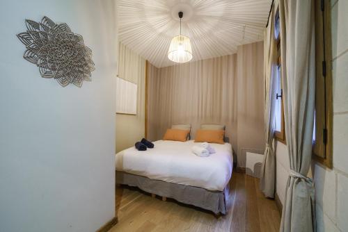 a bedroom with a white bed and a ceiling at La cour du grand marché in Tours