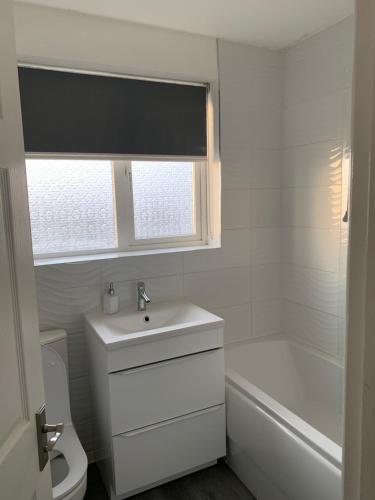 een badkamer met een wastafel, een toilet en een raam bij Adsa Guesthouse in Seacroft