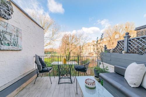 a patio with a couch and a table on a deck at Elgin Terrace in London