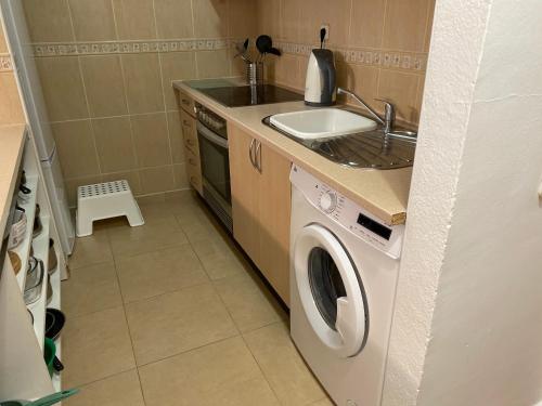 a kitchen with a washing machine and a sink at Estrella Del Mar 8. 1 Bedroom Villa with Pool and Gardens 300 metres from the beach in Corralejo