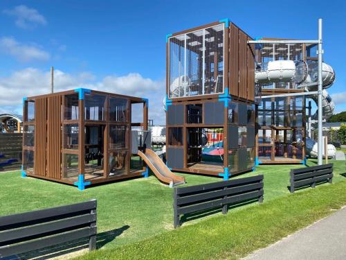 un patio de juegos con tres estructuras de juego en la hierba en Beachhouses Texel, en De Koog
