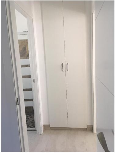 Habitación blanca con armarios blancos y espejo. en Apartamento en Aguiño, en Ribeira