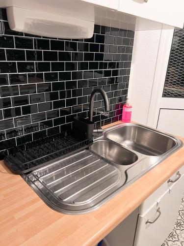 - un évier en acier inoxydable dans une cuisine avec du carrelage noir dans l'établissement Le jardin secret d'Amiens Hypercentre cathédrale, Parking, à Amiens