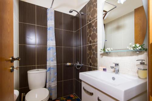 bagno con servizi igienici, lavandino e specchio di Sokaki House a Kalivianí