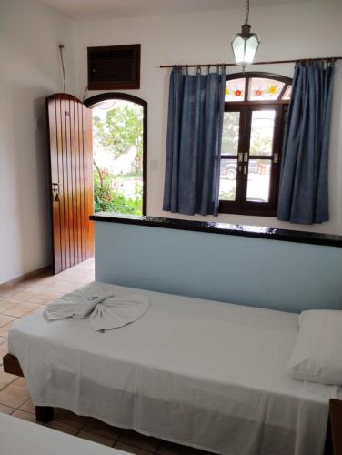 Schlafzimmer mit einem Bett, einem Fenster und einem Spiegel in der Unterkunft Hotel Xaréu in Ubatuba