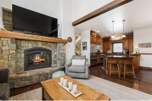 a living room with a stone fireplace and a table at Pinnacle Ridge Luxury Condo 2 in Whitefish
