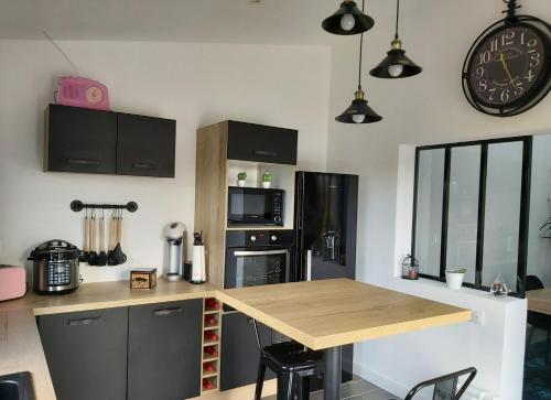 une cuisine avec une table et une horloge au mur dans l'établissement La Réjardière aux portes de Brocéliande, à Iffendic