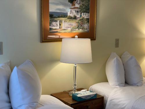 a hotel room with two beds and a lamp on a table at Central House Inn in Bar Harbor