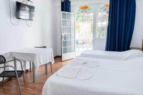 a room with two beds and a table and a window at Pousada Villa Real in Sabará