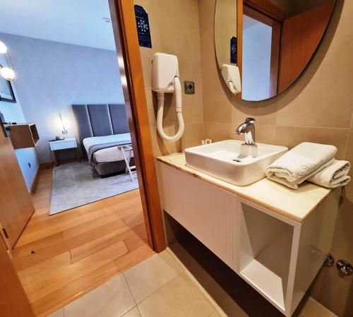 a bathroom with a sink and a mirror and a bedroom at Hotel Albergaria Borges in Chaves