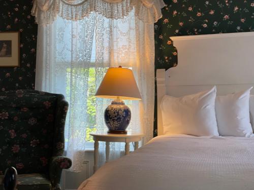 a bedroom with a bed with a lamp and a window at Central House Inn in Bar Harbor