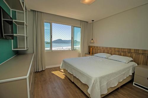 1 dormitorio con cama y ventana grande en Apartamento Frente Mar, en Balneário Camboriú