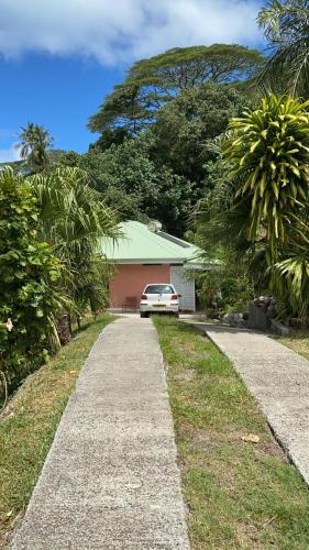 a driveway with a car parked in front of a house at Pension Te Aroha - Te Haumaru in Maatea