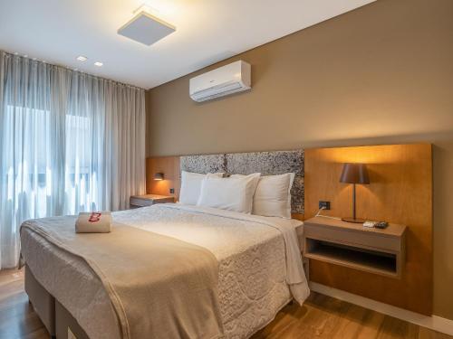 a hotel room with a bed and a window at Allure 102 - Apto em Gramado Av das Hortênsias in Gramado