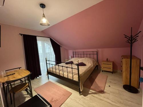 a bedroom with a bed and a table and a window at Pokoje Gościnne Сisza in Białowieża