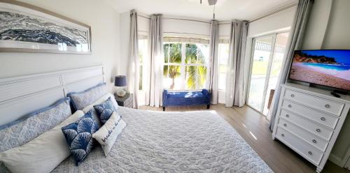 GreenLinks Golf View Villa Flamingo at Lely Resort في نيبلس: غرفة نوم بسرير كبير وتلفزيون