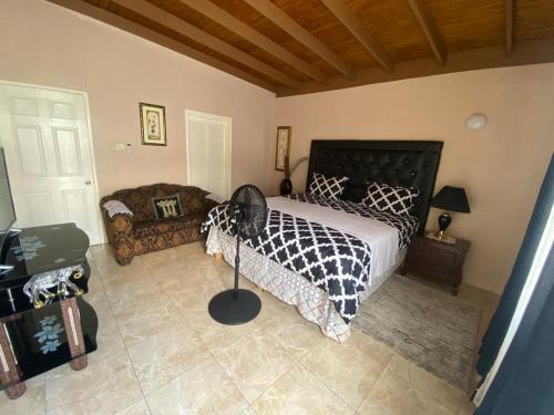 1 dormitorio con cama, ventilador y sofá en Portmore - Cheerful Private Bedroom with Fan only or AC - Choose your room, en Portmore