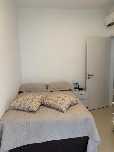 een bed met twee kussens erop bij Apartamento pé na areia em frente a Ilha do Campeche in Florianópolis