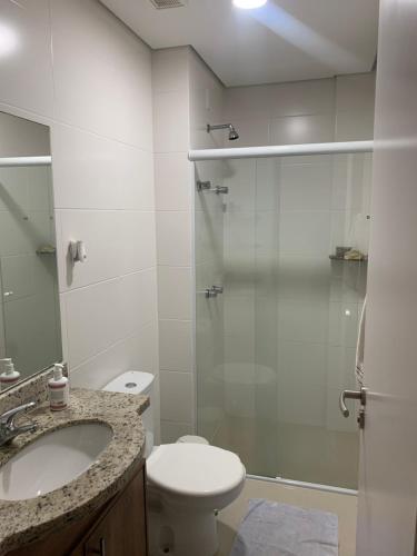 een badkamer met een douche, een toilet en een wastafel bij Apartamento pé na areia em frente a Ilha do Campeche in Florianópolis