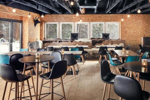 a restaurant with tables and chairs and windows at Mumlava Resort Harrachov in Harrachov