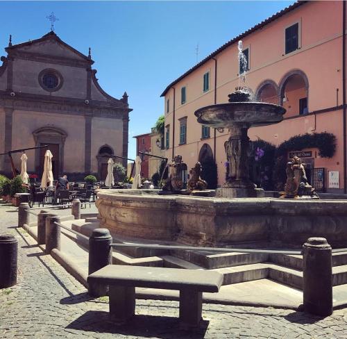 a fountain in a courtyard with a bench in front of a building at Piazza Duomo in Tuscania