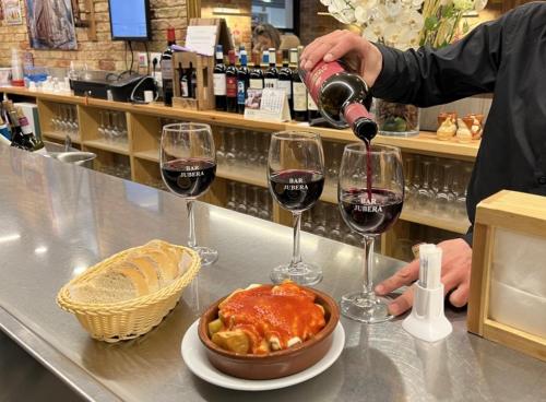 a man pouring wine into two wine glasses at LA TERRAZA DE LAUREL con Aire Acondicionado by Apartamentos Logrono in Logroño