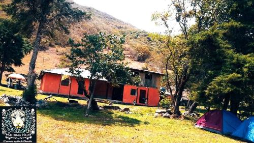 Hütte mit Zelten auf einem Feld mit Bäumen in der Unterkunft Shirma Nua Chaucha in Cuenca