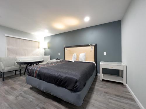 a bedroom with a bed and a desk and a piano at Courtesy Inn & Suites in Rosemead