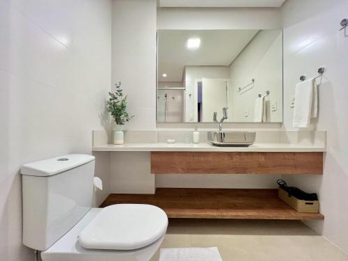 a bathroom with a white toilet and a sink at Apartamento Villaggio Del Veneto 1 dorm by Achei in Canela