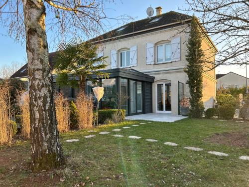 Una casa blanca con un árbol delante. en Les Suites Champenoises en Reims