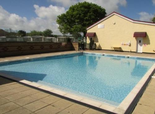 a large blue swimming pool in front of a building at First Steps Caravan Rentals in Sandown