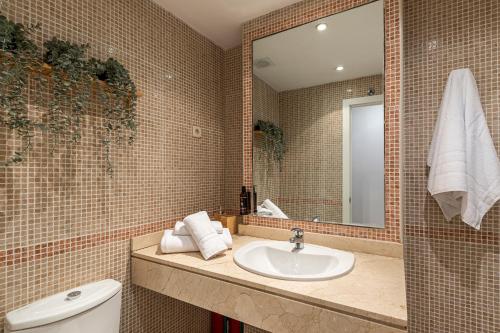 La salle de bains est pourvue d'un lavabo, d'un miroir et de toilettes. dans l'établissement BNBHolder II Santiago Bernabeu, à Madrid
