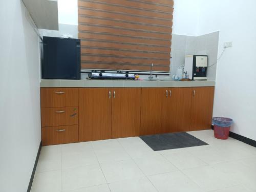 une cuisine avec des placards en bois et une grande fenêtre dans l'établissement Homestay baitijannati, à Pasir Mas