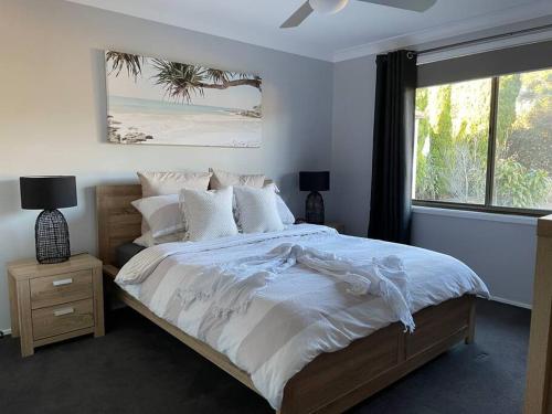 a bedroom with a bed with white sheets and a window at 'Anchor Management' Recently Renovated 3BR / 2BTH in Nelson Bay