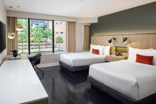 a hotel room with two beds and a window at The Delaney Hotel in Orlando