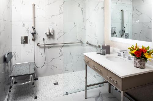 a white bathroom with a sink and a shower at The Delaney Hotel in Orlando