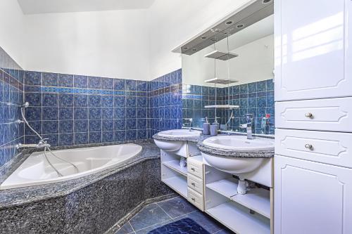 a blue tiled bathroom with a tub and a sink at Villa MARIE-GALANTE -Sainte-Anne in Sainte-Anne