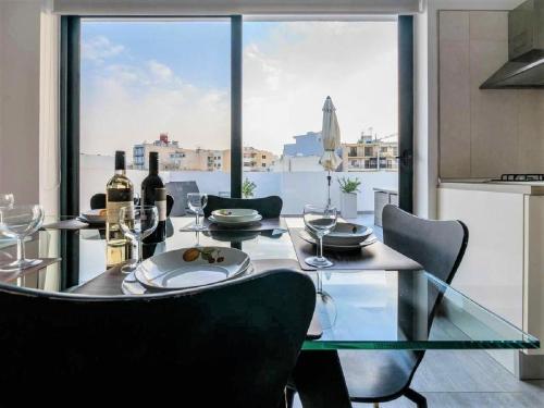 a dining room with a glass table with wine glasses at Bugibba Deluxe Penthouse with terrace & communal swimming pool in St. Paul's Bay