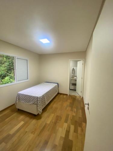1 dormitorio con 1 cama en una habitación con ventana en Quatro Estações Hospeda - Casa Manancial Campos do Jordão, en Campos do Jordão