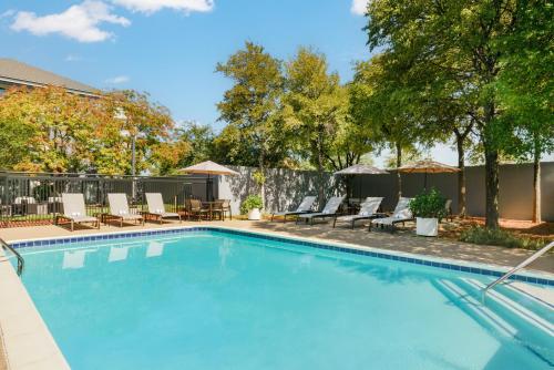 - une piscine avec des chaises longues et des parasols dans l'établissement Courtyard by Marriott Dallas Lewisville, à Lewisville