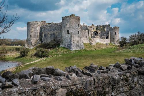 a castle on a hill with a stone wall at Queens Holiday Apartment in Pembroke Dock