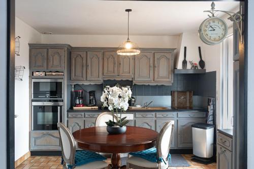une cuisine avec une table, des chaises et une horloge dans l'établissement chambres d hotes les papillons, à Évron