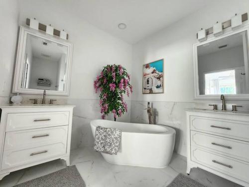 ein weißes Badezimmer mit einer Badewanne, einem Waschbecken und einem Spiegel in der Unterkunft GreenLinks Golf View Villa Flamingo at Lely Resort in Naples