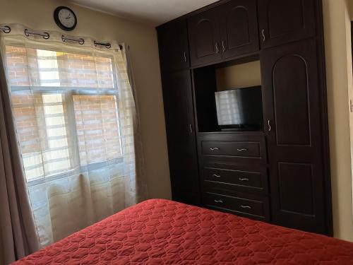 1 dormitorio con 1 cama y vestidor con TV en Apartamento #1 Portal de Occidente en Quetzaltenango